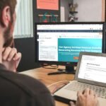 man sitting on chair using silver laptop